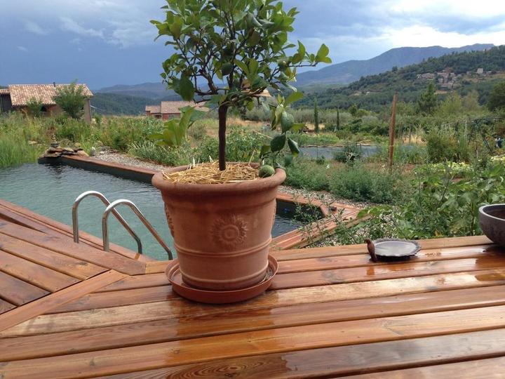 Vue sur le gîte à gauche et sur le paysage depuis la piscine naturelle